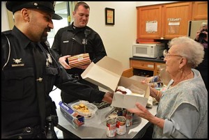 Officer Luigi Gjokaj hands Farnia a birthday cake while partner Mike Fedenis looks on. Farnia will soon be celebrating her 93rd birthday